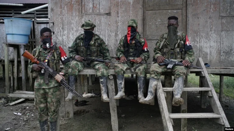 ARCHIVO - Rebeldes del Ejército de Liberación Nacional colombiano descansan afuera de una casa cerca del río San Juan, Colombia, en agosto de 2017.