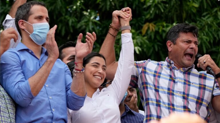 El líder opositor Freddy Superlano habla mientras levanta la mano de su esposa Aurora Silva. El líder de la oposición, Juan Guaido, aparece en la foto a la izquierda. Venezuela, 4 de diciembre de 2021. (AP)