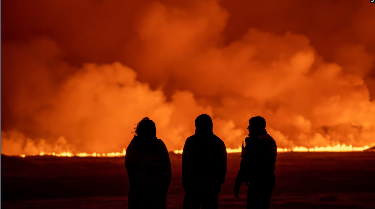 La gente observa cómo el cielo nocturno se ilumina debido a la erupción de un volcán en Grindavik, en la península de Reykjanes, Islandia, el lunes 18 de diciembre de 2023.