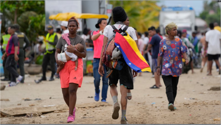 Un migrante lleva una bandera venezolana en Necoclí, Colombia, un punto de parada para los migrantes que toman barcos hacia Acandí que conducen al Tapón del Darién, el jueves 13 de octubre de 2022.