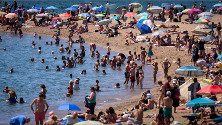 Bañistas se refrescan en el agua mientras otros toman el sol en una playa de Barcelona, España, el 24 de julio de 2024.