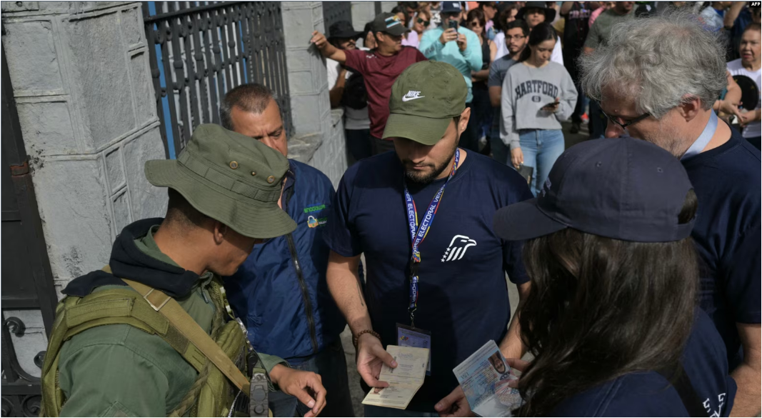 Observadores electorales del Centro Carter muestran sus credenciales a un militar venezolano en la entrada de un centro de votación, el 28 de julio de 2024, en Caracas.