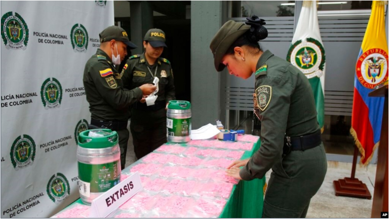 ARCHIVO - Un agente de policía organiza bolsitas llenas de pastillas de MDMA, también conocida como éxtasis, durante una presentación para medios en el Aeropuerto El Dorado de Bogotá, Colombia, el jueves 22 de junio de 2017.